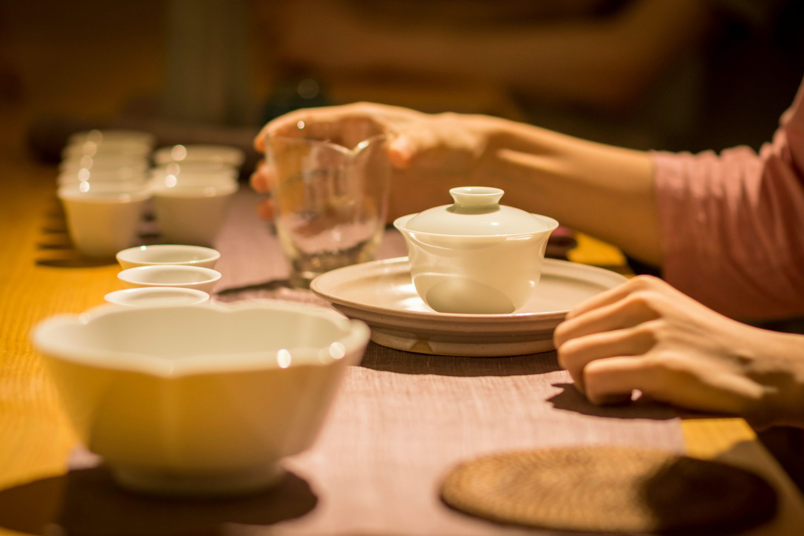 Hands preparing tea at a shared table, expressing tranquility, home rituals, and mindful nourishment